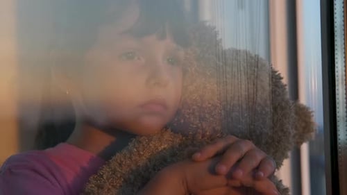 Sad child by the window.