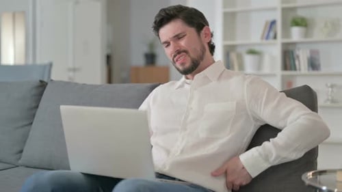 Young Adult Man on Couch with Back Pain