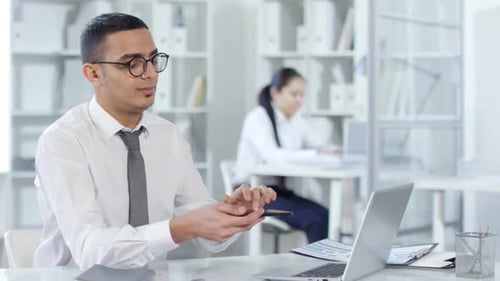 Arab Man Projecting Invisible AR Object from Phone in Office