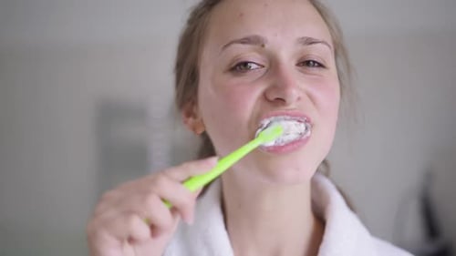 Young Woman Brushing Teeth in Bathroom