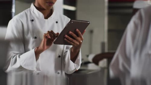 African american female chef using tablet in restaurant kitchen