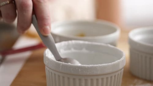 Measuring teaspoon of baking powder into mixing bowl