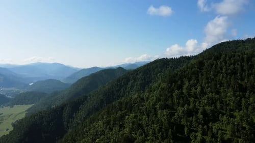 Mountain Peaks Covered with Green Vegetation Against a Blue Sky with Clouds