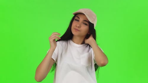 Attractive Girl Puts On Baseball Cap, Green Screen