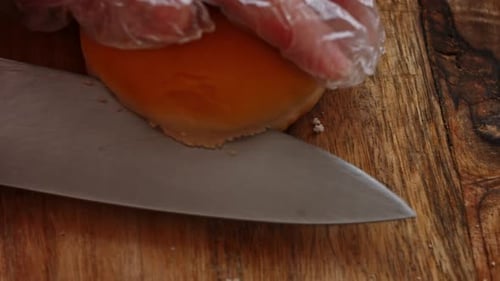 Cutting a Golden Brown Burger Bun on a Wooden Board