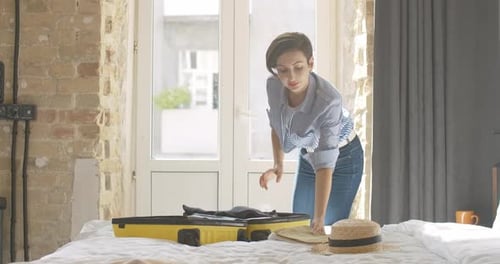 Woman Packing Suitcase in Bright Room