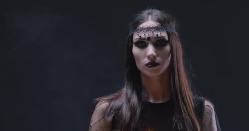 Woman Holding Skull Candle in Dark Arts Setting