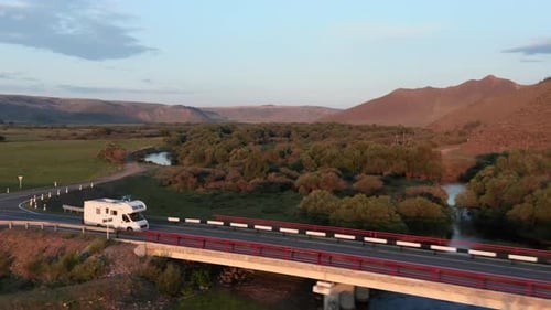 Drone Follows Camper Van Rv From the Side It Sunset on Road in Wilderness