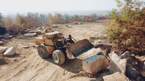 professioneller gelber Bulldozer mit Eimer arbeitet im Steinbruch mit Steinen