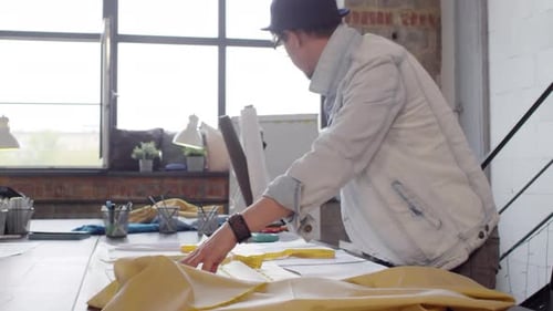 Male Dressmaker Working with Patterns and Fabric in Sewing Studio