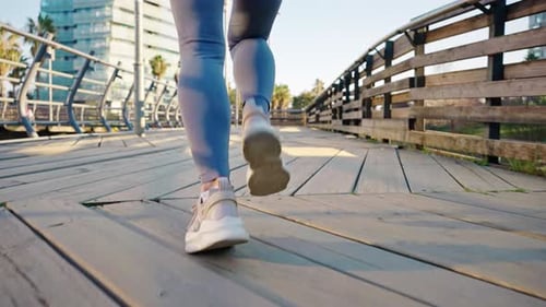 Closeup Legs of Millennial Female Runner Jogging By Wooden Bridge