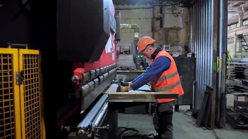 Operator bending metal sheet. Side view of metal processing