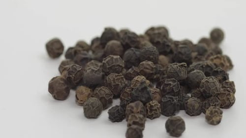 Pile of Black Peppercorns Close Up on White