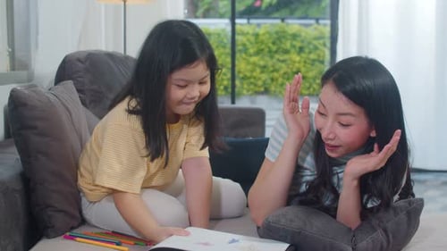 Child Shares Drawing With Mother On Couch
