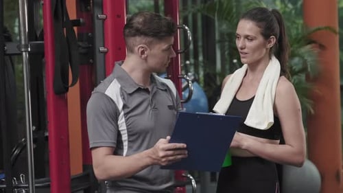 Gym Coach Explaining workout Plan to Woman