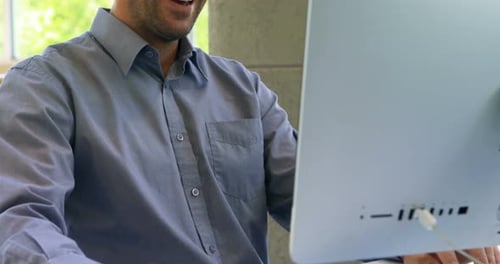 Smiling Man Working on Computer in Modern Office