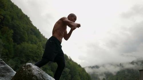 Muscular Man Practicing Boxing in Mountain Landscape