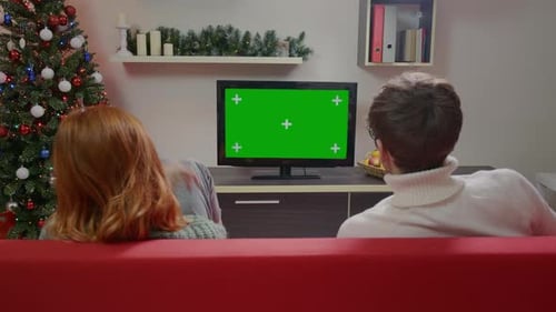 Family couple watching a green screen TV model sitting on the couch in the living room