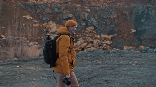 Photographer Walking in a Mountainous Area with Camera