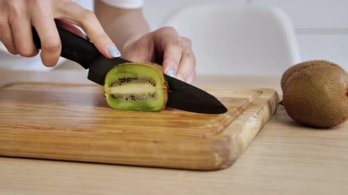 Slicing a Fresh Kiwi Fruit on Cutting Board
