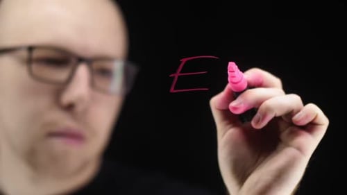 Person Writes Physics Equation on Clear Surface