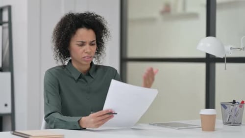 Woman Reviews Documents with Disappointment at Desk
