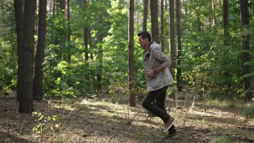 Wide Shot Kaukasier läuft mit Rucksack im Sommerwald im Freien