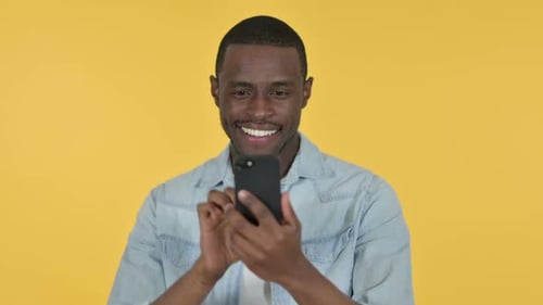 Young Man Smiling and Using Mobile Phone