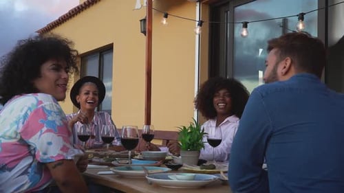 Friends Laughing Together Over Meal and Red Wine