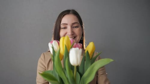 Smiling Woman Smells Colorful Spring Tulips