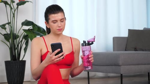 Young Woman Drinks Water After Exercise at Home
