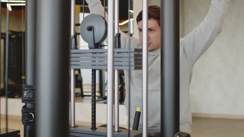 Young Man in Gray Hoodie Training Arms in a Gym