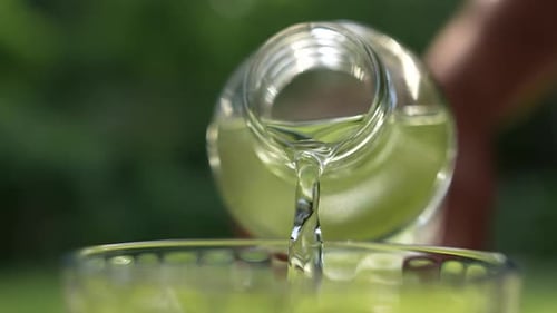 Clear Liquid Poured From Bottle Into Glass