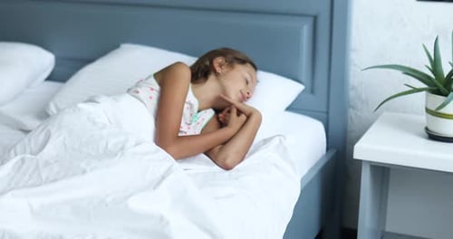 Маленькая девочка спит на большой и уютной постели белого белья