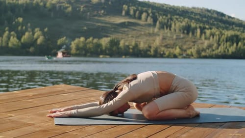 Belle jeune femme faisant du yoga sur une jetée en bois