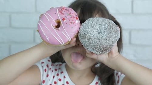 Child with Donuts Sticking Tongue Out