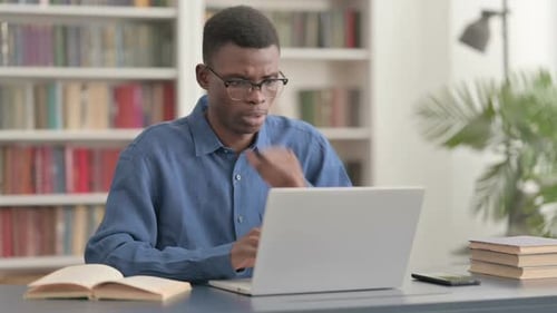 Young African Man Coughing While Using Laptop in Office