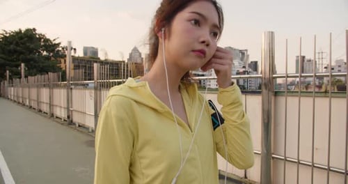Athlete lady exercises using smartphone for listen to music while running in urban city