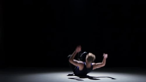 Junger blonder Tänzer beginnt Breakdance auf Schwarz zu tanzen