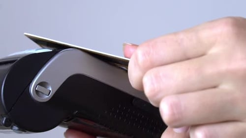 a woman's hand brings a plastic card to the terminal and pays contactless