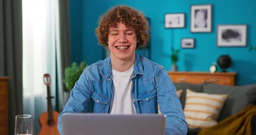 Young Man Excited While Using Laptop at Table