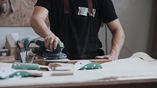 Man Worker Grinding a Wooden Plank in the Workshop Using an Instrument