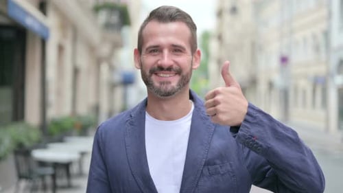 Smiling Young Adult Gives Thumbs Up in City
