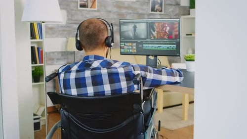 Man in Wheelchair Works on Computer at Home