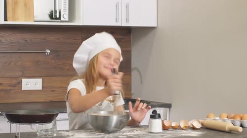 Kaukasisches kleines Mädchen versucht selbständig in der Küche zu backen und Teig in Schüssel zu mischen