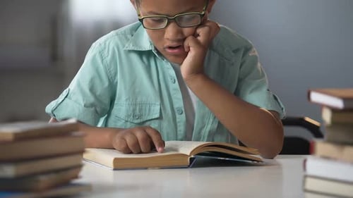 Smart Boy in Glasses Sitting in Library Reading Books, Educational Literature