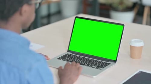Young African Man Using Laptop with Green Screen