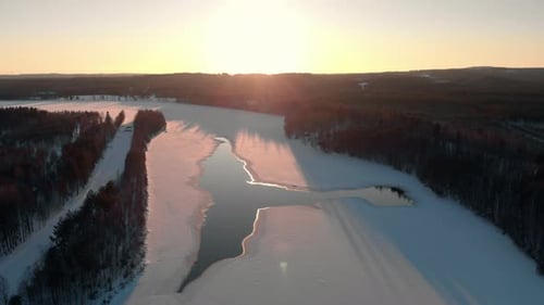 Aerial view of a frozen river with sunset sunlight painting everything warm yellow