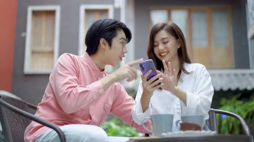 Young couple looking at mobile phone shopping online and share information together in coffee shop