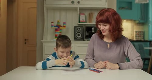 Mother Helping Child with Drawing at Table